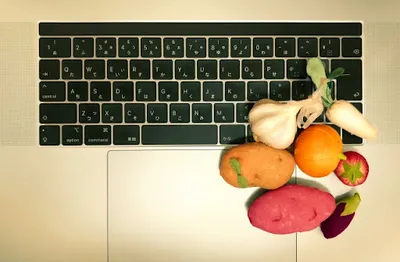 キーボード上に並べられた野菜と果物。食品ドロップシップの扱い商品をイメージ