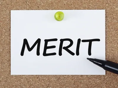 コルクボードに「MERIT」と書かれた紙を黄色いピンで留めたイメージ