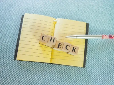 ノートに貼られた「CHECK」の黄色い付箋とペン、タスク管理のイメージ