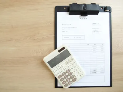 請求書、白い電卓、日本円札がデスク上に配置。経営財務管理のイメージ