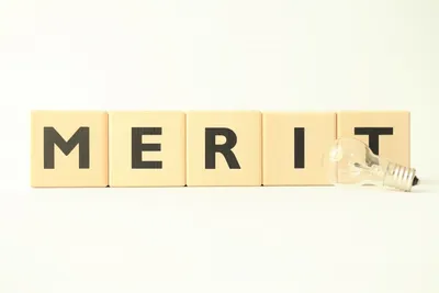 木製キューブに黒文字で「MERIT」と表記。クロスボーダーECのメリット・利点を象徴。