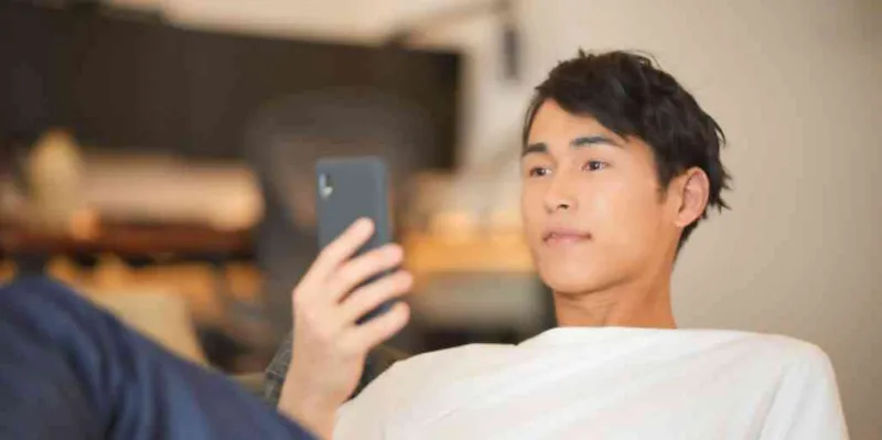 スマートフォンを見ながら考える男性の様子