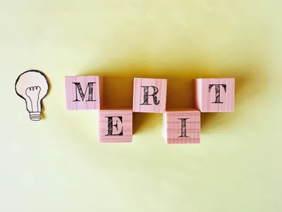 メリット(利点)を象徴するアイデア電球と「MERIT」の木製ブロック