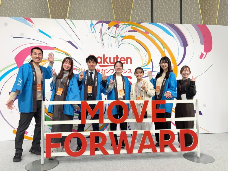 楽天カンファレンス会場で「MOVE FORWARD」バナーの前に立つ登壇者7人