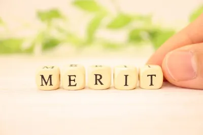 MERITと刻まれた木製ブロックを持つ人の指