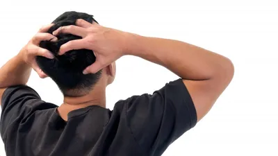 頭を両手で抱えて困惑と悩みを示す男性
