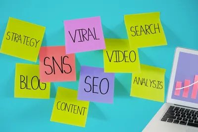 SNS、SEO、動画、ブログなどマーケティング施策キーワードの付箋、ノートパソコン