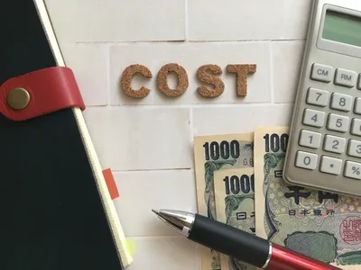 ノート、電卓、日本円札、ペンが机上に配置。経営管理と予算計画の概念図