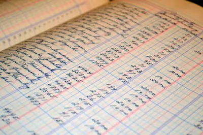 方眼紙のノートに手書きされた商品・在庫管理用の表格やデータ記録、管理帳票
