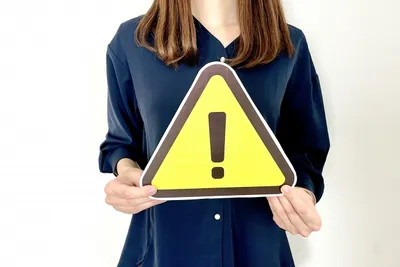 黄色の注意信号を掲げる女性で過剰在庫リスクを警告喚起