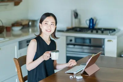 RMS画面を操作する女性スタッフ。タブレット端末でコーヒーを持ちながら業務中