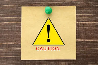 黄色い注意標識の付箋に黒い感嘆符と「CAUTION」のテキスト、セール施策実施時の注意点を象徴するイメージ