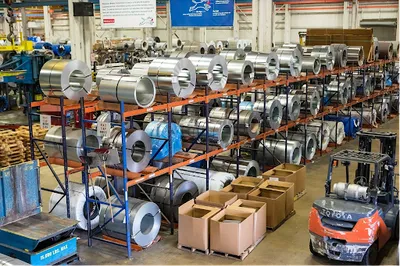 オレンジ色の金属ラックに大量のステンレス製品が保管された大規模産業倉庫