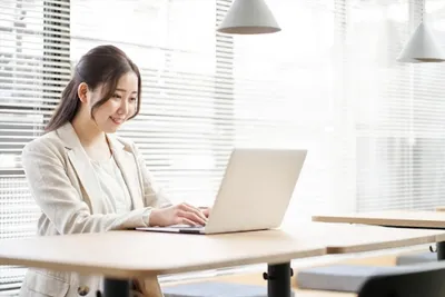 朝日差すオフィスでノートパソコンを操作する女性の受注メール対応