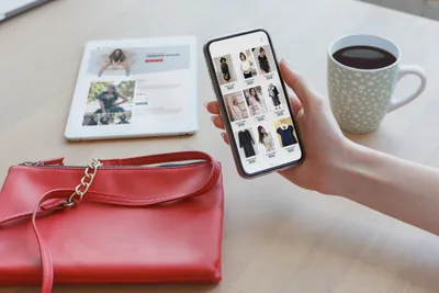 スマートフォン画面でファッション商品を閲覧する女性の手。EC利用者・オンライン購買体験。