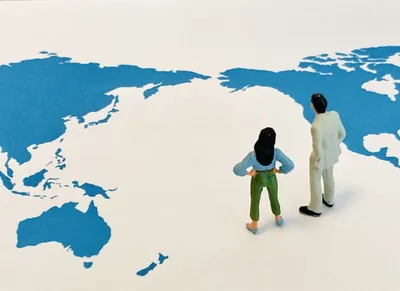 世界地図上にビジネスパーソン2人が立つ。グローバルな国際EC取引を表現。
