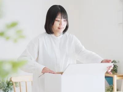 白背景でノートパソコンの前に立つ女性