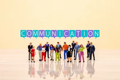 虹色の複数吹き出しで「COMMUNICATION」と表示。様々な色彩の人物が並ぶ。多様なコミュニケーション。